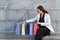 Girl examines purchases in colored shopping bags while sitting on street