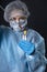 Girl examines a test tube with biomaterial. Young woman in protective clothing. On the face of a protective medical mask