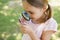 Girl examining butterfly with magnifying glass at park