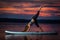 Girl exercising yoga on paddleboard in the sunset on scenic lake Velke Darko