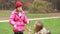 Girl explaining game to her mom in park, dad coming and hugging her