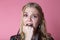 Girl in fear closes fist open mouth, curly blonde on pink background