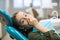 Girl in fear closes his mouth with his hands in the dental clinic.