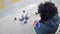 Girl feeding flock of pigeons on town square