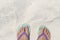 Girl feet in blue slippers on sand beach texture. Tropical seashore. Seaside banner template with text place.