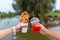 The girl and fella during the walk holds in hands a paper cup with a Belgian waffle and fresh drink on a background of green park