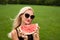 The girl on the field in photochromic glasses a black hat holds a watermelon from behind a beautiful forest