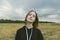 Girl in a field posing on a background of storm clouds outside the city in a field. Beautiful girl stands in a field and looks