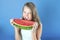 Girl fiercely biting a piece of watermelon.