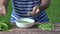 Girl finger hulled fresh peas in plate wooden table outdoor. 4K