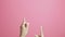 Girl fingers pointing up, girl advertises actively gesticulating on pink studio background