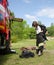 Girl in fireman`s suit against a fire engine preparing to overcome an obstacle course