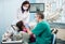 Girl with on the first dental visit. Senior pediatric dentist with nurse treating patient teeth at the dental office