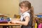 A girl first-graders attentively listens to teacher at school