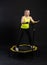 Girl on a fitness trampoline on a black background in a yellow t-shirt trampoline sport, equipment female healthy weight