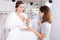 Girl fitting wedding dress with help of shop assistant