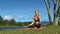 Girl fixes yoga pose against green bank blue sky