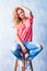 Girl fixing her hair while posing and sitting on a chair