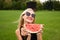 Girl flirts on the field with black glasses. An appetizing slice of watermelon. Dark hat behind beautiful forest