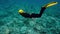 Girl floating under water. Elegant woman in black wetsuit and yellow fins diving into depths. Flexible scuba diver