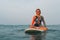 Girl floats sitting on the surf on horseback and smiling