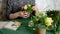 Girl florist straightens leaves on a pot of flowers.