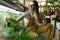 Girl florist work in greenhouse with plants for home garden, flower shop. Woman gardener in orangery