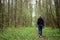 Girl with flowers on a path in the forest. The grass is green near tall slender trees. Young trees stately row. In the middle