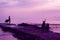 Girl in a fluttering dress and a moped standing on the old sea pier against the background of the sea and sunset.