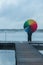 Girl in the fog on the pier with a rainbow umbrella looking into the distance, view from the back