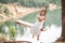 A girl in the forest swinging on a swing. Rope swing on a forest lake. Barefoot girl in a white dress with long hair