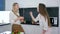 Girl with a fork in her hands feeding her girlfriend a vegetable salad, young women laughing cheerfully in kitchen