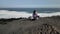 Girl freelancer sits on a cliff near the ocean with a laptop