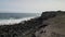 Girl freelancer sits on a cliff near the ocean with a laptop