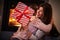 Girl friends exchanging Christmas presents over fireplace