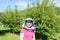 A girl in a fruit garden wearing a beekeeper`s hat