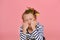 A girl with a funny hairstyle in a striped T-shirt touches her hair, is surprised and makes funny faces