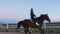 A girl galloping on horseback at outdoor manege