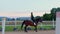 A girl galloping on horseback at outdoor manege