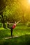 Girl in garden doing standing half bow pose.