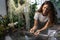 Girl gardener taking care about aquatic plant in greenhouse holding houseplant under bath with water