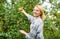 Girl gather apples harvest garden autumn day. Farmer lady picking ripe fruit from tree. Harvesting concept. Woman hold