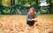 Girl gathering autumn leaves in park