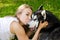 The girl gently kisses the husky dog in the park on the grass. Close-up.
