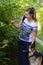 Girl with german shepherd among green trees on summer day