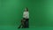 Girl a girl is sitting half-turned, on a suitcase, looking at the left on green screen