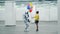 A girl is giving balloons to a cyborg in an empty hall