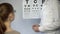 Girl in glasses looking at table letters, eyesight examination, ophthalmologist