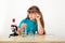 A girl with glasses makes experiments with a microscope