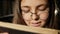 Girl with glasses reading a book in the library, close-up